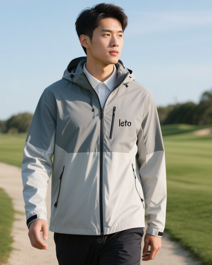 A golfer wearing a modern, lightweight windproof jacket, swinging confidently on a windy golf course with trees swaying in the background.
